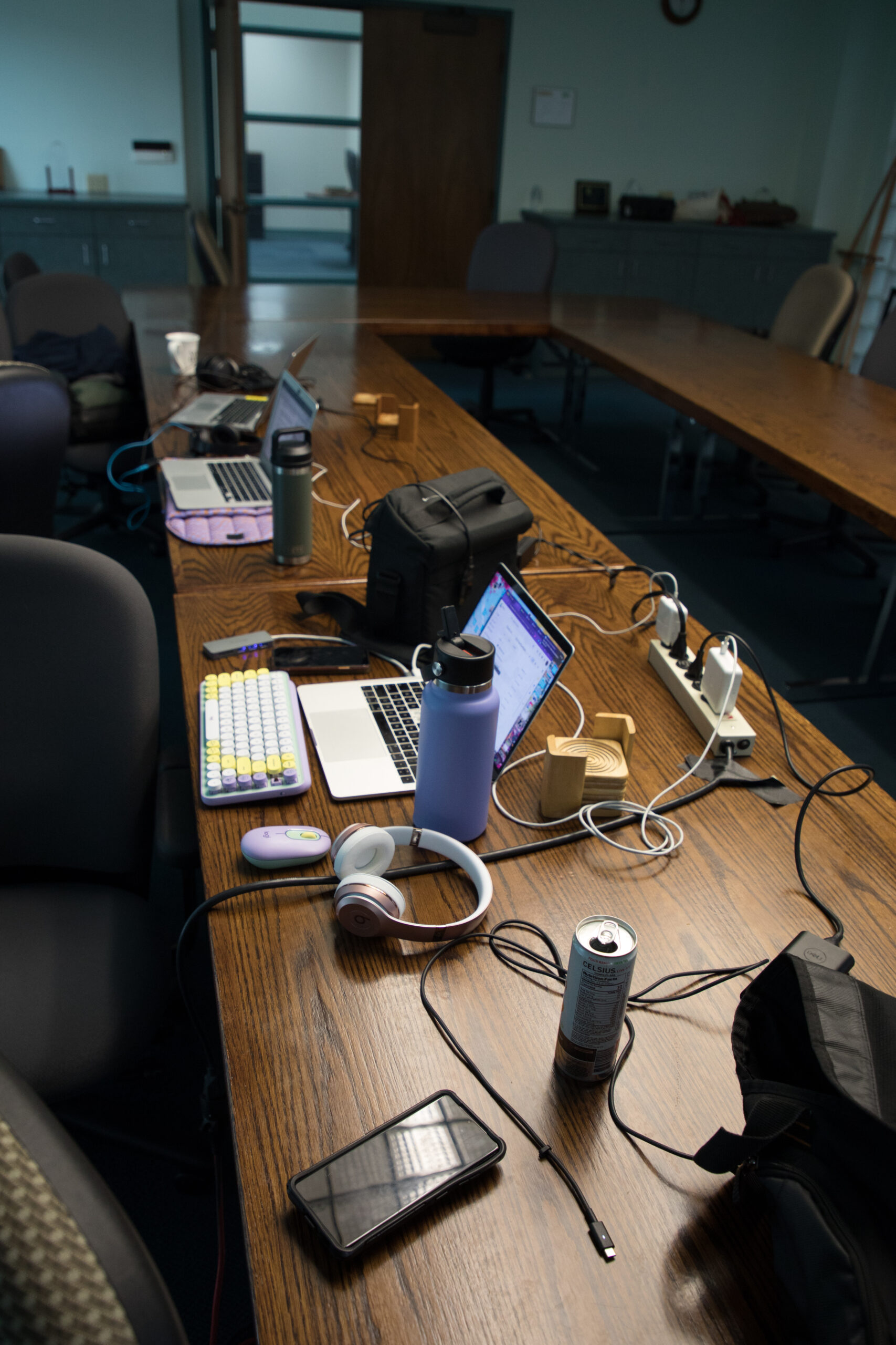Laptops, cords, headphones and drinks are on a brown table.
